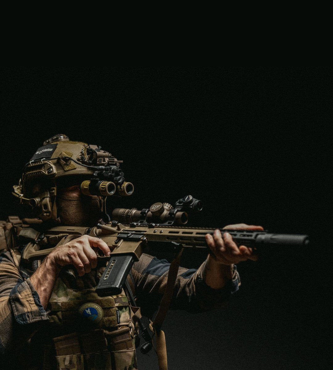 Operator aiming a suppressed rifle under night vision